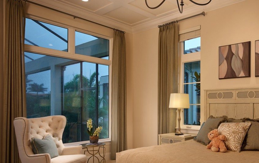 Cozy bedroom with large windows and beige curtains.